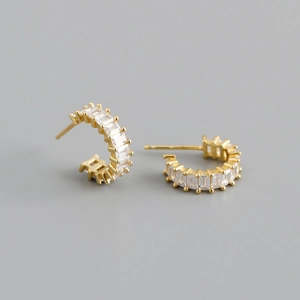 Detail view of gold C-shape stud earrings featuring rectangle-cut clear cubic zirconia stones