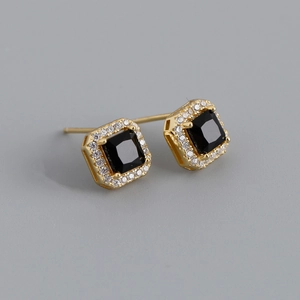 Macro detail of square halo stud earrings featuring black zircon and gold plating finish