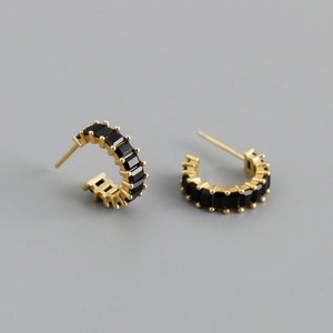 Detailed view of gold C-shaped earrings set with rectangular black zircon stones