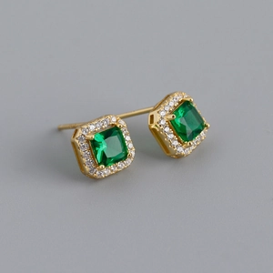 Macro view of princess-cut emerald zircon earrings with gold-plated diamond halo