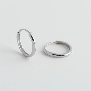 Dettaglio di orecchini a cerchio minimalisti in argento sterling S925 lucido a specchio
