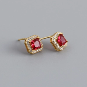 Close-up of square red zircon earrings with gold plating and white stone halo