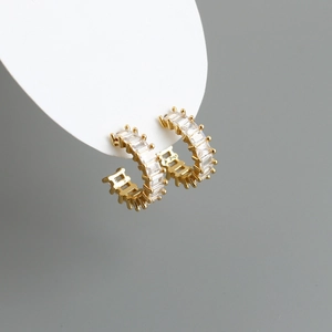 Detail view of gold C-shape hoop earrings featuring baguette-cut sparkling cubic zirconia