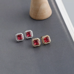 Macro shot of square red zircon stud earrings with halo diamonds in gold and silver