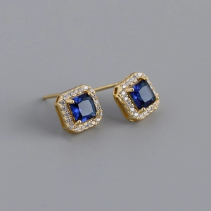 Macro view of square blue gemstone earrings with white diamond halo and gold pins