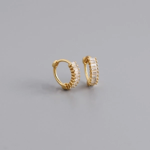Detailed macro view of gold-plated silver huggie earrings with baguette-cut cubic zirconia
