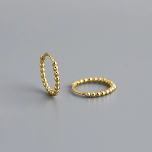 Close-up of golden S925 sterling silver hoop earrings with a beaded dot texture design