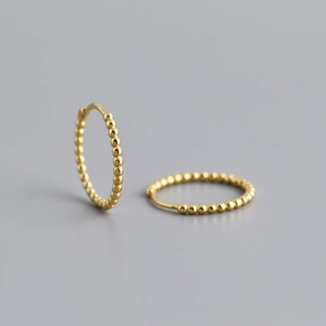 Detailed close-up of golden beaded hoop earrings made of sterling silver for women