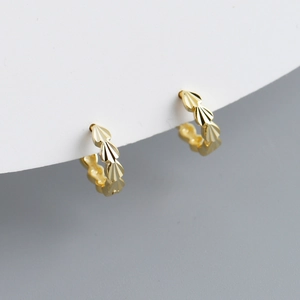 Macro detail of gold huggie earrings featuring radial fan-shaped engraved patterns