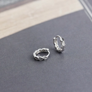 Macro detail showing S925 hallmark on polished silver hoop earrings with textured patterns