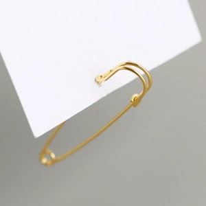 Macro-opname van gouden veiligheidsspeld oorbel op witte kaart met metalen glans