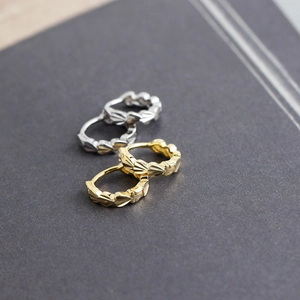 Macro shot of S925 sterling silver hoop earrings showing intricate engraved heart patterns