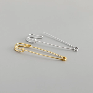 Macro-opname van minimalistische s925 zilveren veiligheidsspeld oorbellen in goud en zilver