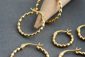 Detailed view of gold S925 sterling silver hoop earrings with bead textured design