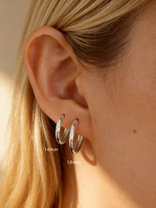 Detail view of 14mm and 18mm polished sterling silver hoop earrings on a model