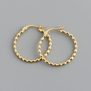 Macro detail of gold beaded hoop earrings with S925 sterling silver hallmark