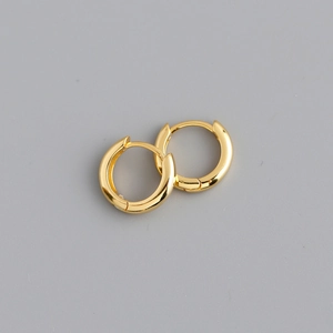 Macro shot of minimalist gold plated hoop earrings with a high-polished smooth surface