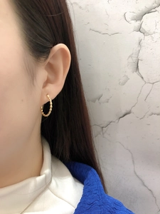 Detail of gold hoop earrings with beaded texture on model for a French chic style look