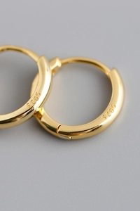 Macro shot of S925 sterling silver stamp on polished gold plated hoop earrings