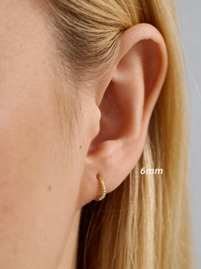 Gros plan d'une créole dorée de 6mm avec texture perlée sur un modèle féminin