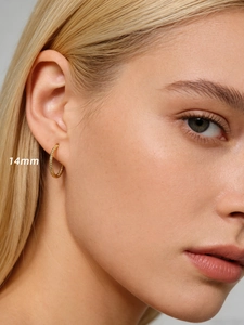 Gros plan d'une créole torsadée dorée de 14mm portée à l'oreille d'un mannequin