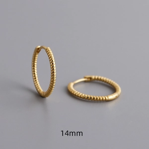 Vue détaillée de créoles torsadées dorées de 14mm avec un motif en spirale texturé