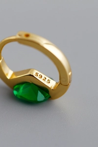 Macro del marchio S925 su orecchino a cerchio dorato con zircone verde a goccia