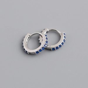 Vue macro de boucles d'oreilles créoles S925 avec zircons bleu foncé micro-paves
