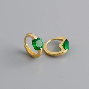 Dettaglio macro di orecchini huggie in argento S925 placcato oro con zirconi verde smeraldo