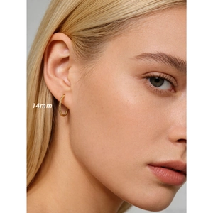 Créoles torsadées dorées de 14mm portées par un mannequin pour un look chic et tendance