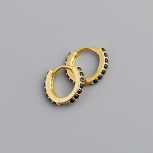 Gros plan de boucles d'oreilles huggie dorées ornées de pierres zircons noires
