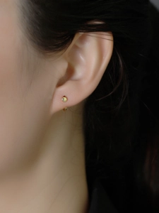 Nahaufnahme eines 18K Gold Ohrsteckers mit Schraubmotiv am Ohr für einen minimalen Look