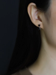 Macro view of S925 silver stud earrings with black teardrop zircon on a model ear