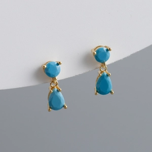 Detail of drop earrings featuring blue teardrop zircon stones in gold s925 silver settings