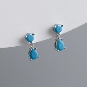 Detail of silver drop earrings featuring teardrop blue zircon in a classic claw setting