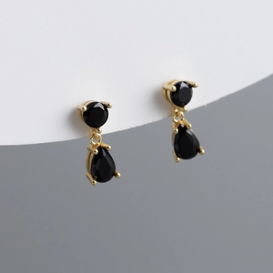 Detailed close-up of pear-shaped black zircon drop earrings in gold-plated claw setting