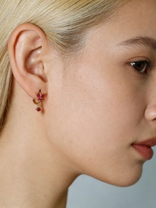 Detailed view of model wearing a gold butterfly earring with sparkling red gemstones