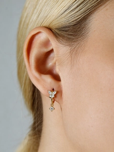 Detail of gold butterfly earring with sparkling cubic zirconia on female model