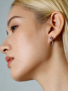 Macro shot of silver butterfly hoop earring with purple zirconia stones on a model