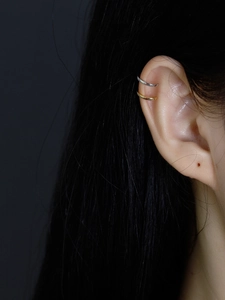 Close-up of gold and silver S925 sterling silver ear cuffs on a model's ear