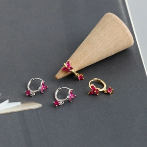 Close-up of golden and silver butterfly earrings with magenta stones on wood cones