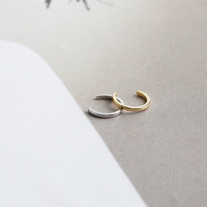 Detail of minimalist S925 sterling silver ear cuffs in polished gold and silver finishes