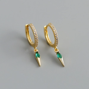 Macro shot of gold hoop earrings with white zircons and green marquise gemstone drops
