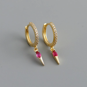 Close-up of gold hoop earrings with white zircon stones and marquise red ruby pendants