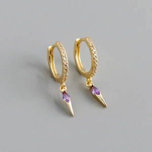 Detailed macro view of gold hoop earrings with purple marquise stone and zircon accents