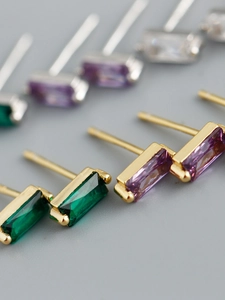 Close-up of baguette-cut zircon stud earrings in emerald green and lavender purple