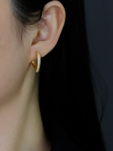 Gros plan d'une boucle d'oreille en argent S925 dorée avec zircons blancs sur un modèle