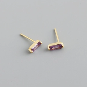 Macro shot of gold-plated silver stud earrings with rectangular purple zircon gemstones
