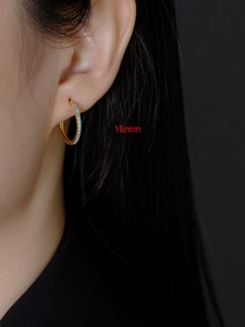 Detailopname van 18mm gouden oorringen met turquoise zirkoon gedragen door model