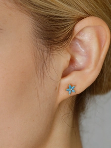 Dettaglio degli orecchini a fiore in argento S925 con petali blu cielo indossati sull'orecchio